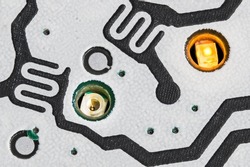 Lit and non-lit LED diode in small holes of PCB detail from dismantled cellphone. Close-up of electronic light emitting sources for buttons backlight. Printed circuit board inside mobile phone keypad.