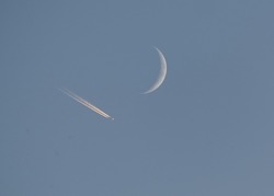 plane flying high by a crescent moon