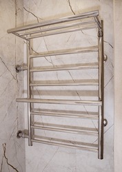 Modern stainless steel water heated towel rail hanging on the wall in the bathroom