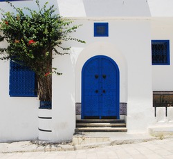 Traditional blue Tunisian metal door with a black pattern in a white building in the city of Sidi Bou Said in Tunisia in the summer on a sunny day