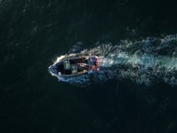 Top down aerial drone footage of a fisherman on hi small fishing boat while underway.