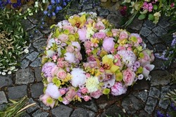 Heart shaped grave arrangement with pink, yellow and white flowers