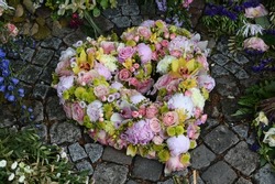 Heart shaped grave arrangement with pink, yellow and white flowers