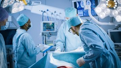 Diverse Team of Professional surgeon, Assistants and Nurses Performing Invasive Surgery on a Patient in the Hospital Operating Room. Real Modern Hospital with Authentic Equipment.