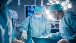 Diverse Team of Professional surgeon, Assistants and Nurses Performing Invasive Surgery on a Patient in the Hospital Operating Room. Surgeon Use Instruments. Modern Hospital with Authentic Equipment.