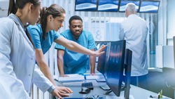 Diverse Team of Medical Scientists Solve Problems and Point at Computer Screens Showing CT, MRI Scans. Neurologists / Neuroscientists Working in Brain Research Laboratory.
