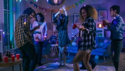 At the College House Party: Diverse Group of Friends Have Fun, Dancing and Socializing. Boys and Girls Dance in the Circle. Disco Neon Strobe Lights Illuminating Room.