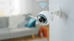 Close Up Object Shot of a Modern Wi-Fi Surveillance Camera with Two Antennas on a White Wall in a Cozy Apartment Has Wi-Fi Icon Above it.