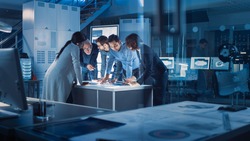 Engineers Meeting in Technology Research Laboratory: Engineers, Scientists and Developers Gathered Around Illuminated Conference Table, Talking and Finding Solution Inspecting Industrial Engine Design