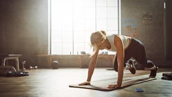 Beautiful and Young Girl Doing Running Plank Exercise on Her Fitness Mat. Athletic Woman Does Mountain Climber Workout in Stylish Hardcore Gym