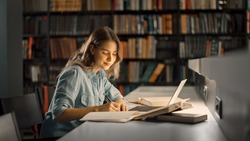 University Library: Beautiful Smart Caucasian Girl uses Laptop, Writes Notes for Paper, Essay, Study for Class Assignment. Focused Students Learning, Studying for College Exams. Side View Portrait