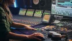 Beautiful, Stylish Female Audio Engineer, Producer Working in Music Recording Studio, Uses Mixing Board, Software to Create Cool Song. Creative Girl Artist Musician Working.