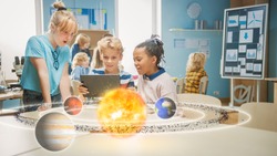 Three Diverse School Children in Science Class Use Digital Tablet Computer with Augmented Reality Software, Looking at Educational 3D Animation Of Solar System. VFX, Special Effects Render