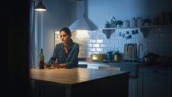 Portrait of Beautiful Lonely Young Woman Drinking from a Wine Glass in the Dark Kitchen. Depressed and Sad Adult Girl with Alcohol Problem Drinks Alone, Bad Relationships, Work Stress, Other Problems