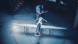 Meeting of Aerospace Engineers Work On Unmanned Aerial Vehicle / Drone Prototype. Aviation Experts have Discussion. Industrial Facility with Aircraft Capable of GPS Surveillance and Military Missions