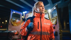Portrait of a Female EMS Paramedic Proudly Standing in Front of Camera in High Visibility Medical Orange Uniform with 
