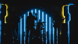 Four Man Rock Band with Lead Singer, Guitarists, Bassist and Drummer Performing at a Concert in a Night Club. Live Music Party in Front of Bright Colorful Strobing Lights on Stage.