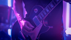 Rock Band Performing at a Concert in a Night Club. Close Up Shot of a Five String Bass Guitar Played by a Musician. Live Music Party in Front of Bright Colorful Strobing Lights on Stage.