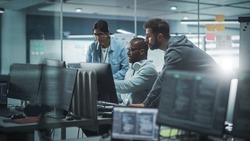 Diverse Group of Professionals Meeting in Modern Office: Brainstorming IT Programmers Use Computer Together, Talk Strategy, Discuss Planning. Software Engineers Develop Inspirational App Program