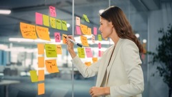 Young Confident Businesswoman Creating Project Plan on Office Wall with Paper Notes. Stylish Beautiful Manager Working on Business, Financial and Marketing Projects. Specialist in Diverse Team.