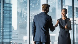 Female and Male Business Partners Meet in Office, Shake Hands. Corporate CEO and Finance Manager Have Meeting in City Office. Businesspeople Came to Discuss Real Estate Purchase and Marketing Project.