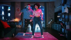 Beautiful Stylish Multiethnic Couple in Casual Outfits and Futuristic Neon Glowing Glasses, Dance and Enjoy Life at Home in Loft Apartment. Recording Funny Viral and Active Videos for Social Media.