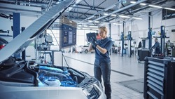 Female Mechanic Uses a Tablet Computer with an Augmented Reality Diagnostics Software. Specialist Inspecting Car's V6 Engine to Quickly Spot Broken Components. Premium Car Service.