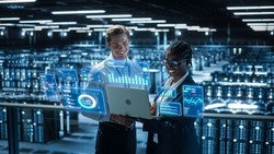 Technical Engineer and Project Administrator Using Computer in Modern Data Center Server Room Facility. Augmented Reality Productivity and Business Data Icons Appear From Worker's Laptop.