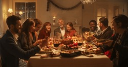 Multi-Generational Family Members Share Funny Stories and Joy During a Christmas Turkey Dinner. Happy Parents and Kids Singing Christmas Carols Together, Dancing Behind a Table and Lighting Sparkles