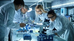 Team of Medical Research Scientists Collectively Working on a New Generation Experimental Drug Treatment. Laboratory Looks Busy, Bright and Modern.
