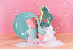 creative still life in bright colors with a sponge in the shape of a unicorn. The unicorn will say through the mountains of dirty dishes filled with foam for washing dishes surrounded by soap bubbles