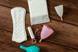 Different types of feminine menstrual hygiene materials products such as pads cloths tampons and cups. wooden background. Menstruation and feminine hygiene concept. 