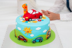 Children's colorful fondant birthday cake decorated with little cars and number one on the top.