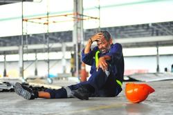 Senior worker accident fall of the scaffolding and headache with broken leg in construction site health insurance concept.