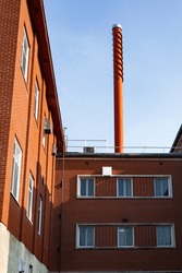A tall chimney on an old industrial red brick building