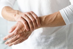 Closeup of male arms holding his painful wrist caused by prolonged work on the computer, laptop. Carpal tunnel syndrome, arthritis, neurological disease concept. Numbness of the hand