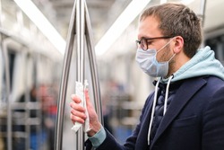 Close up of man holds a handrail in public transportsubway through a napkin, to protect yourself from contact with viruses, germs during a coronavirus pandemic, covid-19. Quarantine concept