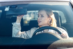 Woman drives her car for the first time, tries to avoid a car accident, is very nervous and scared, worries, clings tightly to the wheel, looking in the rearview mirror. Inexperienced driver in stress