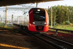 Modern russian intercity high speed train under the bridge at sunset. Industrial landscape with passenger train on railroad in Europe. Commercial suburban transportation concept