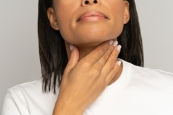 Cropped image of woman touching sore throat. African american female suffer from swallowing difficulty, angina, cold, gland inflammation or coronavirus infection symptoms. Illness and health concept
