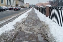 Closeup view of technical salt grains on icy sidewalk surface in wintertime, used for melting ice and snow. Applying salt to keep roads clear and people safe in winter weather from ice or snow