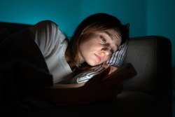 Unhappy woman lying in bed with smartphone, following ex-boyfriend on social media, sad female using mobile phone at night, can not sleep after relationship breakup, suffering from insomnia. Anxiety.