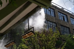 Fogging outdoor cool misting system working hot summer day for terrace in cafe. Facility that lowers temperature by spraying fine mist. Air conditioning and water spray system for cooling and fog.