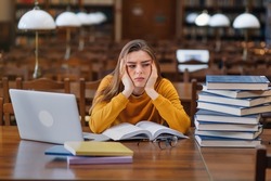 Stressed college student tired of hard learning with books and laptop in exams tests preparation, overwhelmed high school teen girl exhausted with difficult studies or too much homework.