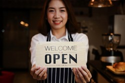 Close-up of a beautiful Asian woman holding a sign to open a coffee shop. Conceptual entrepreneurs, SME businesses, small food service restaurants.