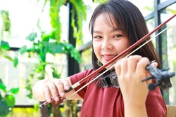 Asian woman playing classical instrument violin at home in the morning. She enjoys playing music. international music education concept Learning and practicing. Band and live music