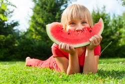 Happy little girl with watermelon in a garden