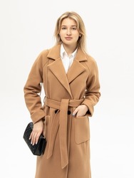 Woman in beige coat with black handbag on white background. Warm coat for autumn or winter. Lined coat with belt