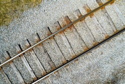 View of old abandoned railroad track from above. Rusty weathered railway track rails. Aerial view down of the rusty train railway track. 
