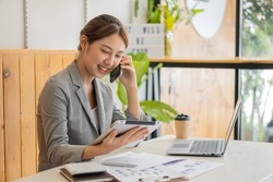Asian woman, self-employed, focusing on mobile phone with the laptop. Financial analysis, graphs, accounts, charts, online marketing plans, working concepts based on coffee shops outside the home.